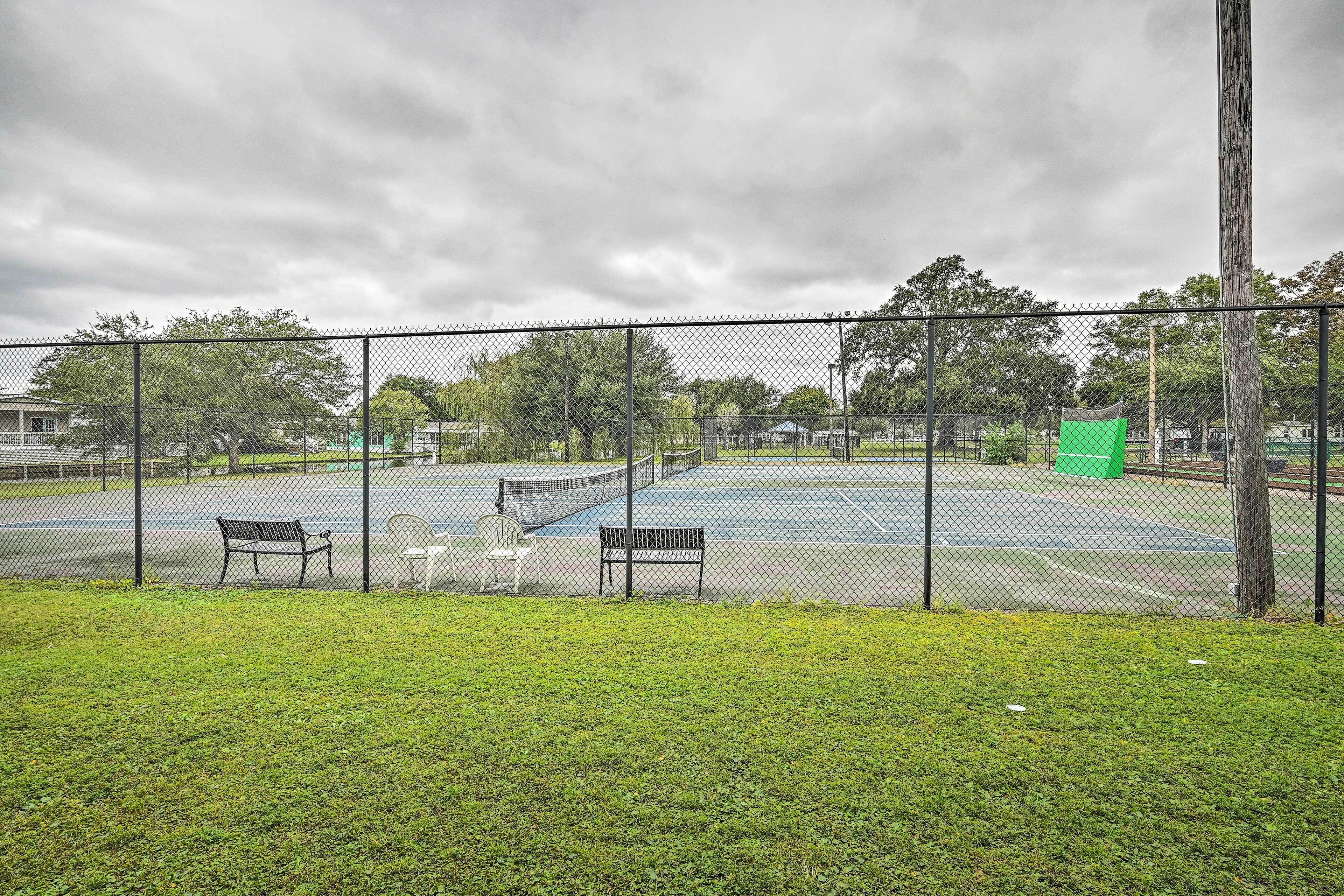 A tennis court with benches and a fence.