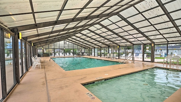 A covered swimming pool with clear water, surrounded by lounge chairs and a view of the outside. - Walk to Shore: Myrtle Beach House w/ Private Deck! (Murrells Inlet)
