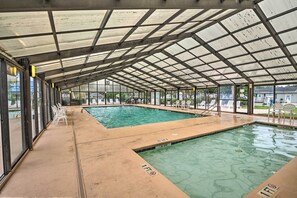 A covered swimming pool with clear water, surrounded by lounge chairs and a view of the outside. - Walk to Shore: Myrtle Beach House w/ Private Deck! (Murrells Inlet)