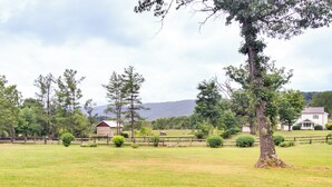 A rural landscape with a large tree, a wooden fence, and a house in the background. - Monticello Wine Trail Cottage - Close to Hiking! (Afton)