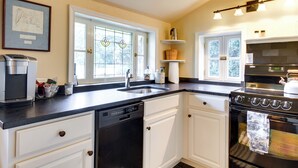 A kitchen with white cabinets, a black stove, and a dishwasher. - Monticello Wine Trail Cottage - Close to Hiking! (Afton)