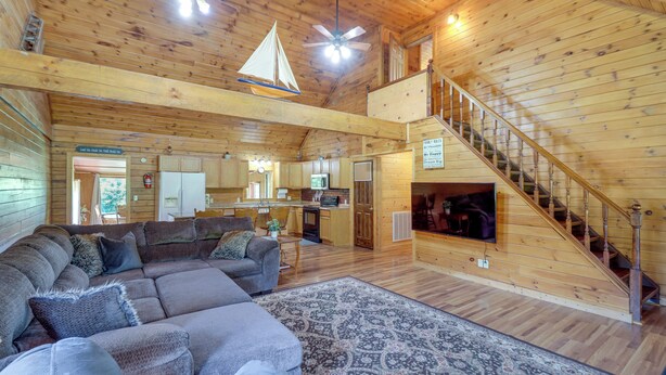 A spacious living area with a large sectional sofa, a patterned rug, and a wooden staircase leading to an upper level. - Secluded Harrison Retreat Near Buffalo Natl River (Harrison)