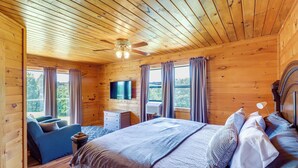 A wooden cabin bedroom with a bed, a TV, a dresser, and a sofa. - Secluded Harrison Retreat Near Buffalo Natl River (Harrison)