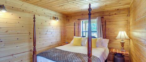 A wooden cabin bedroom with a four-poster bed, a nightstand, and a lamp.