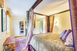 Un dormitorio con una cama grande, un banco, un tapete y un dosel.