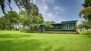 A modern building with a green roof and large windows, surrounded by lush green grass and trees. - Waterfront Georgetown Retreat on Lake George! (Georgetown)