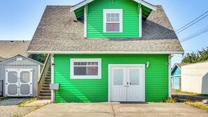 A two-story building with a green exterior, a white front door, and a window with 'OPEN' and 'E-FILE TAX' signs. - Walkable Paradise: Downtown Puyallup Studio! (Puyallup)