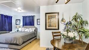 A bedroom with a bed, a bedside table, a lamp, and a window with curtains. - Walkable Paradise: Downtown Puyallup Studio! (Puyallup)