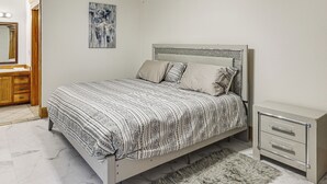 A bedroom with a bed, a nightstand, a mirror, and a ceiling fan.