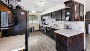 A modern kitchen with dark wood cabinets, a built-in island, stainless steel appliances, and a tiled backsplash.