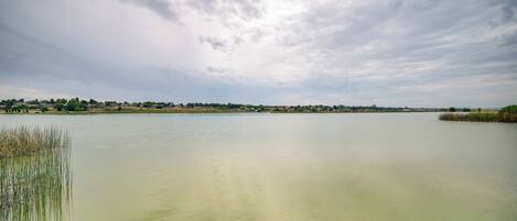 Um lago calmo com uma linha de costa distante e céu nublado.