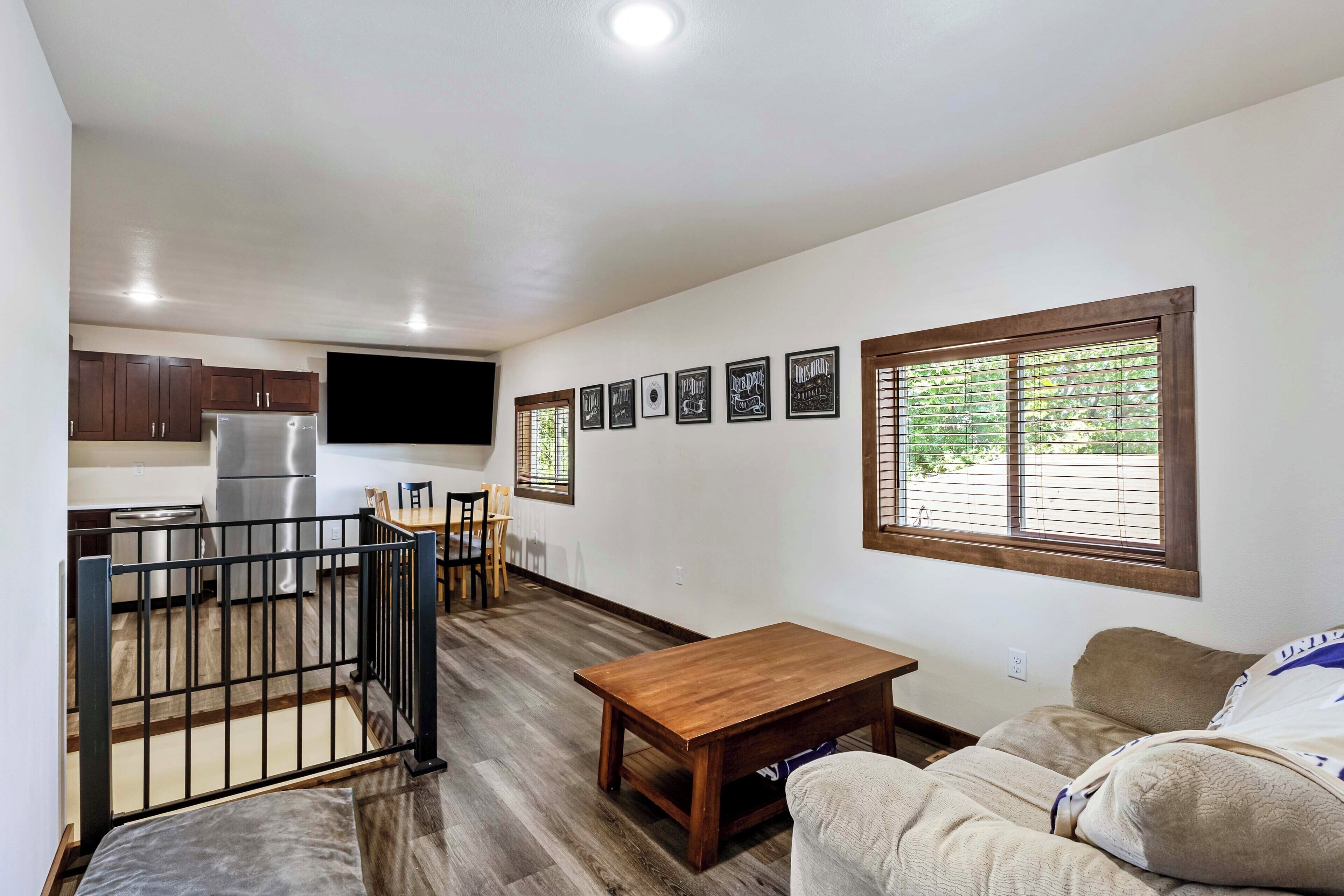 Eine moderne Küche mit Kühlschrank, Herd und Essbereich. Im Wohnbereich befindet sich ein Holztisch und eine Couch.