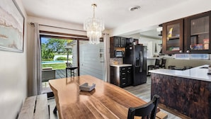 A modern kitchen with a wooden dining table, dark cabinetry, and a large island.