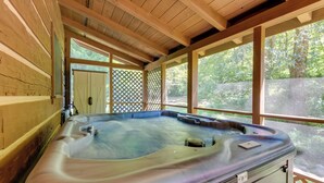 A wooden cabin with a hot tub and large windows. - Cabin w/ Hot Tub + Fishing Pond in Del Rio! (Hartford)