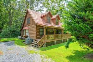 A wooden cabin with a porch, surrounded by lush greenery. - Cabin w/ Hot Tub + Fishing Pond in Del Rio! (Hartford)