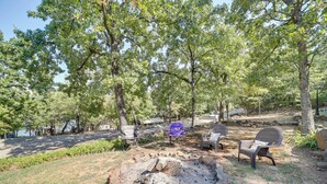 A campsite with a fire pit, several chairs, and a view of a lake. - Lake Eufaula Retreat w/ Boat Slip & Fireplace! (Stigler)