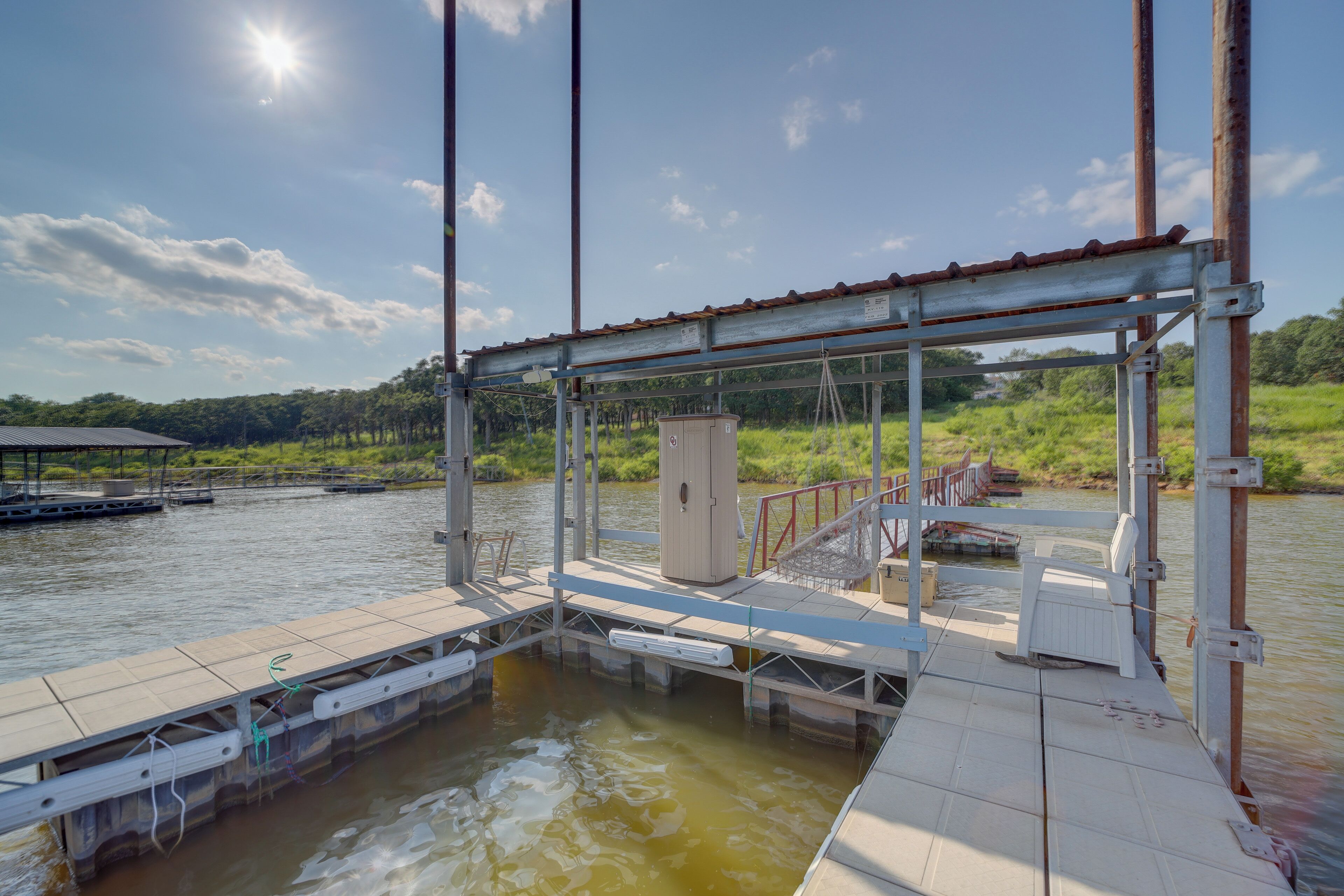 A dock with a covered area, a small utility box, and a chair.