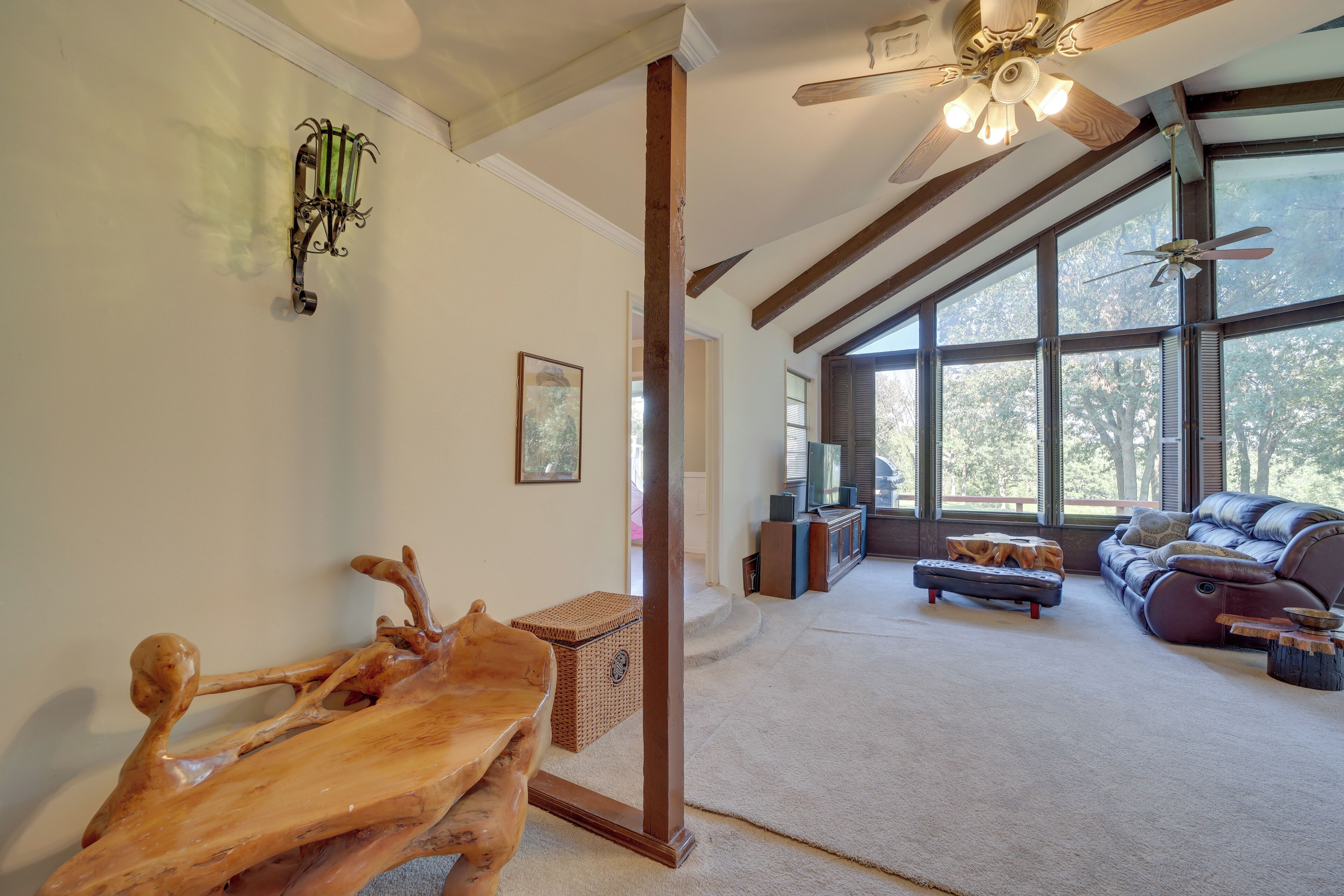 A spacious living room with a large window, a ceiling fan, and a wooden coffee table.