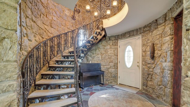 Eine prächtige Wendeltreppe mit Steinwänden und einem Klavier im Zwischenpodest.