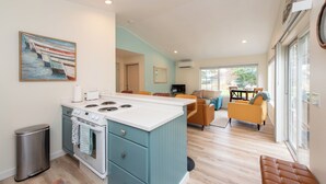 A modern kitchen with a central island, a dining area with a table and chairs, and a living room with a sofa and armchairs. - Sequim Escape w/ Gas Grill & Deck, Walk to Beach! (Sequim)