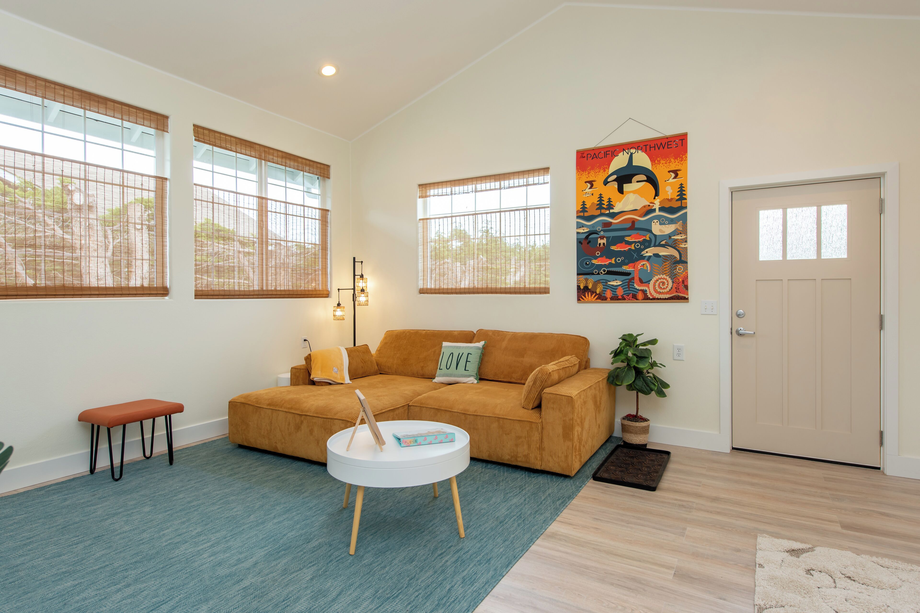 A living room with a brown sofa, a white coffee table, a bench, and a large poster on the wall.