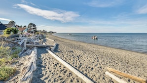 A sandy beach with driftwood and a wooden fence. - Sequim Escape w/ Gas Grill & Deck, Walk to Beach! (Sequim)