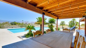 A covered outdoor dining area with a pool, wooden chairs, and a view of mountains. - Chic Borrego Springs Home w/ Outdoor Oasis! (Borrego Springs)