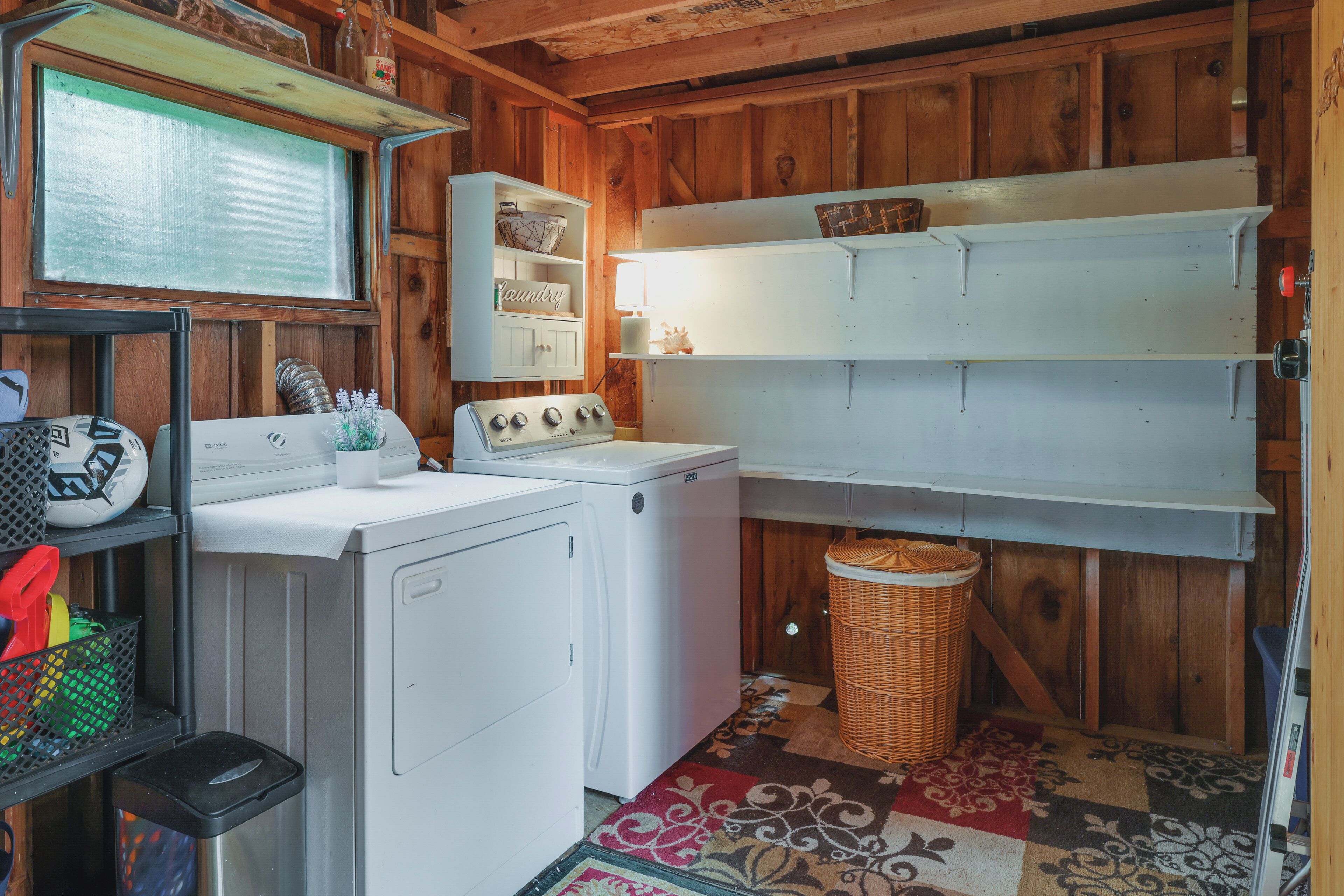 A laundry area with a washing machine, dryer, shelves, and a basket.