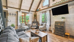 Una sala de estar acogedora con techo de madera, televisor grande y chimenea.
