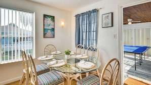 A dining area with a glass table, wicker chairs, and a view of the ocean. - Ormond Beach Home: Walk to Community Beach! (Ormond Beach)