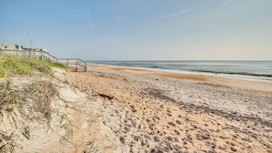 A sandy beach with a wooden walkway leading to a building. - Ormond Beach Home: Walk to Community Beach! (Ormond Beach)