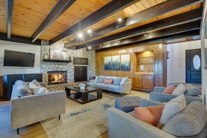 A spacious living room with a fireplace, sofas, and a television. - Lake Views, Game Room, Decks, 3 Ks, 2 Qs, 6 Baths! (Lake Arrowhead)