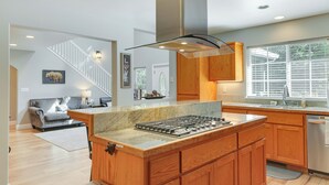 A modern kitchen with wooden cabinets, a central island with a stove, and a built-in dishwasher. - Near Dtwn: Twain Harte Home w/ Furnished Deck! (Twain Harte)