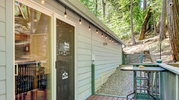 A deck with a table and chairs, a glass door, and a string of lights. - Near Dtwn: Twain Harte Home w/ Furnished Deck! (Twain Harte)