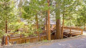 A wooden bridge with a railing, surrounded by trees and a building with a red roof. - Cozy Mi-wuk Village Cabin w/ Deck! (Mi-Wuk Village)
