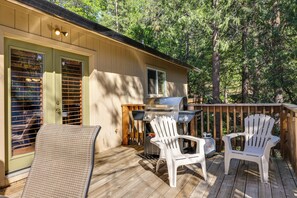 A deck with two white Adirondack chairs and a grill, surrounded by a wooden deck and trees. - Cozy Mi-wuk Village Cabin w/ Deck! (Mi-Wuk Village)