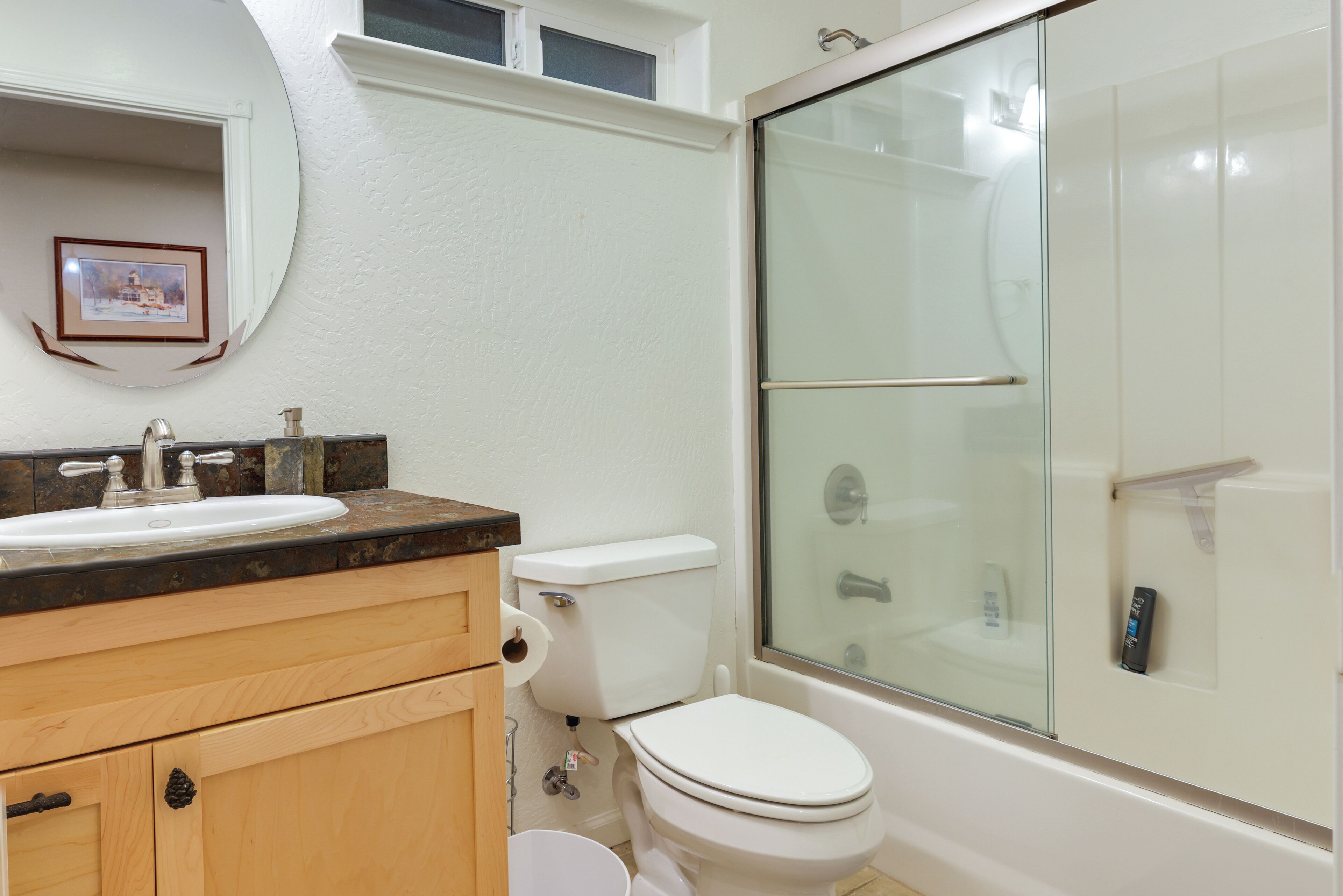 A bathroom with a white sink, toilet, and glass-enclosed shower.