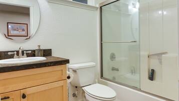 A bathroom with a white sink, toilet, and glass-enclosed shower.