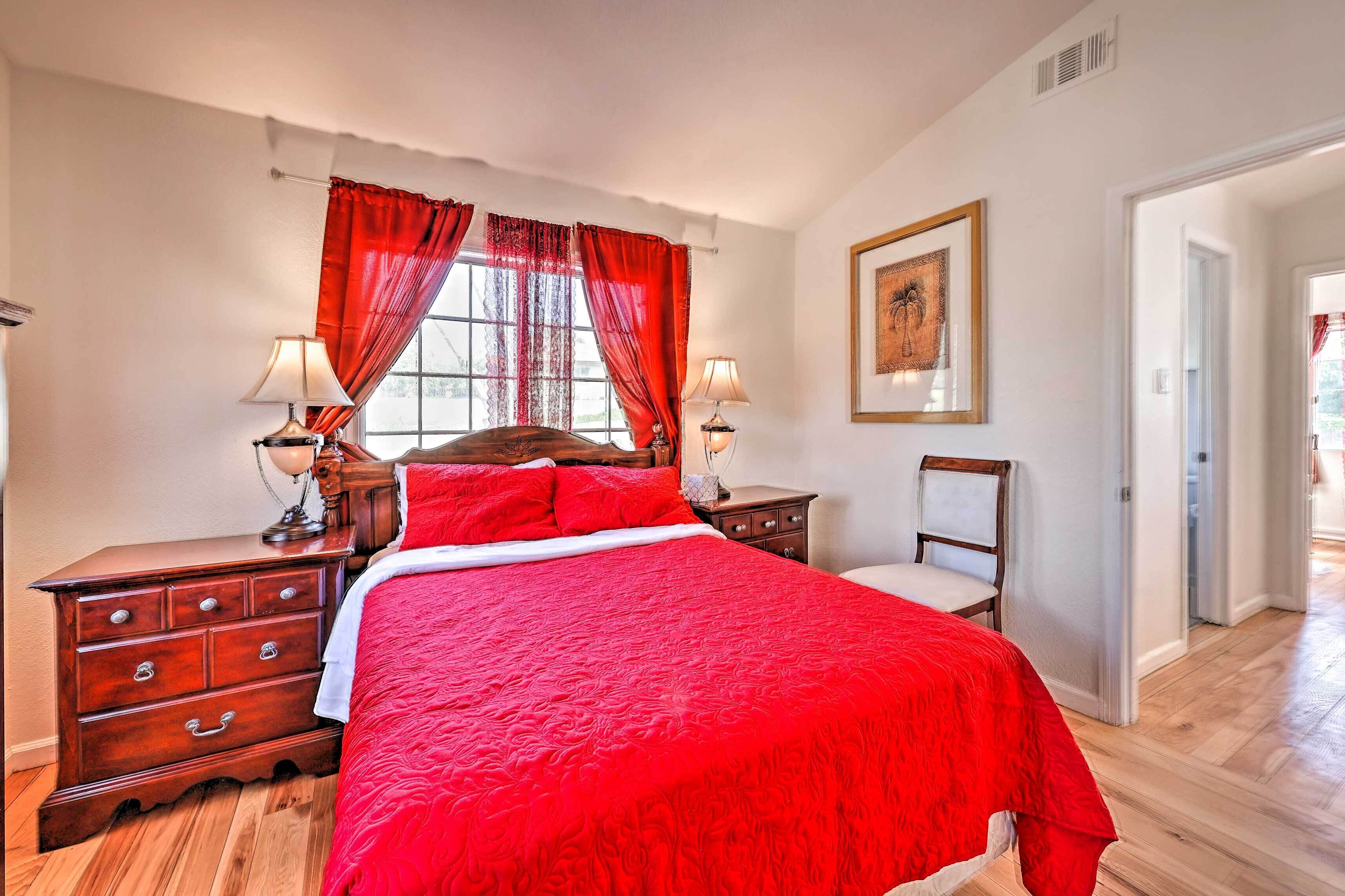 A bedroom with a large bed, two bedside tables, a wooden dresser, and a chair.