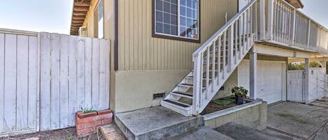 Une maison de plain-pied avec un porche à l’avant, une clôture en bois et un escalier menant à la porte d’entrée.