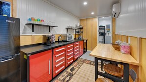 Une cuisine moderne équipée d’un réfrigérateur, de meubles de rangement rouges, d’une table à manger en bois et d’un îlot central.
