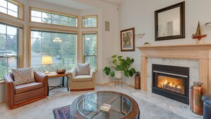 A living room with a fireplace, a glass coffee table, a sofa, and a chair. - Family-friendly Hot Tub Home in Bonney Lake (Bonney Lake)