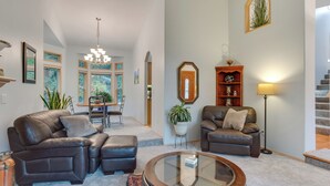 A spacious living room with a large sectional sofa, a glass coffee table, and a dining area with a chandelier. - Family-friendly Hot Tub Home in Bonney Lake (Bonney Lake)