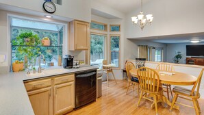 A modern kitchen with wooden cabinets, a dishwasher, and a dining area with a wooden table and chairs. - Family-friendly Hot Tub Home in Bonney Lake (Bonney Lake)