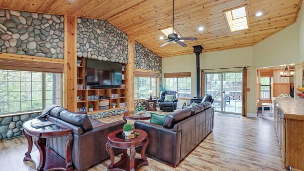 A spacious living room with a stone wall, leather sofas, a fireplace, and a large TV. - Mi-wuk Village Vacation Rental w/ Multi-level Deck (Mi-Wuk Village)