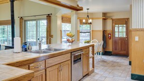 A kitchen with wooden cabinets, a stainless steel sink, and a built-in oven. There is a window with blinds, a door with a doormat, and a ceiling light fixture. - Mi-wuk Village Vacation Rental w/ Multi-level Deck (Mi-Wuk Village)