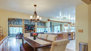 A spacious kitchen with a large island, wooden countertops, and a stone backsplash. There is a dining area with a wooden table and chairs, and a chandelier above. - Mi-wuk Village Vacation Rental w/ Multi-level Deck (Mi-Wuk Village)