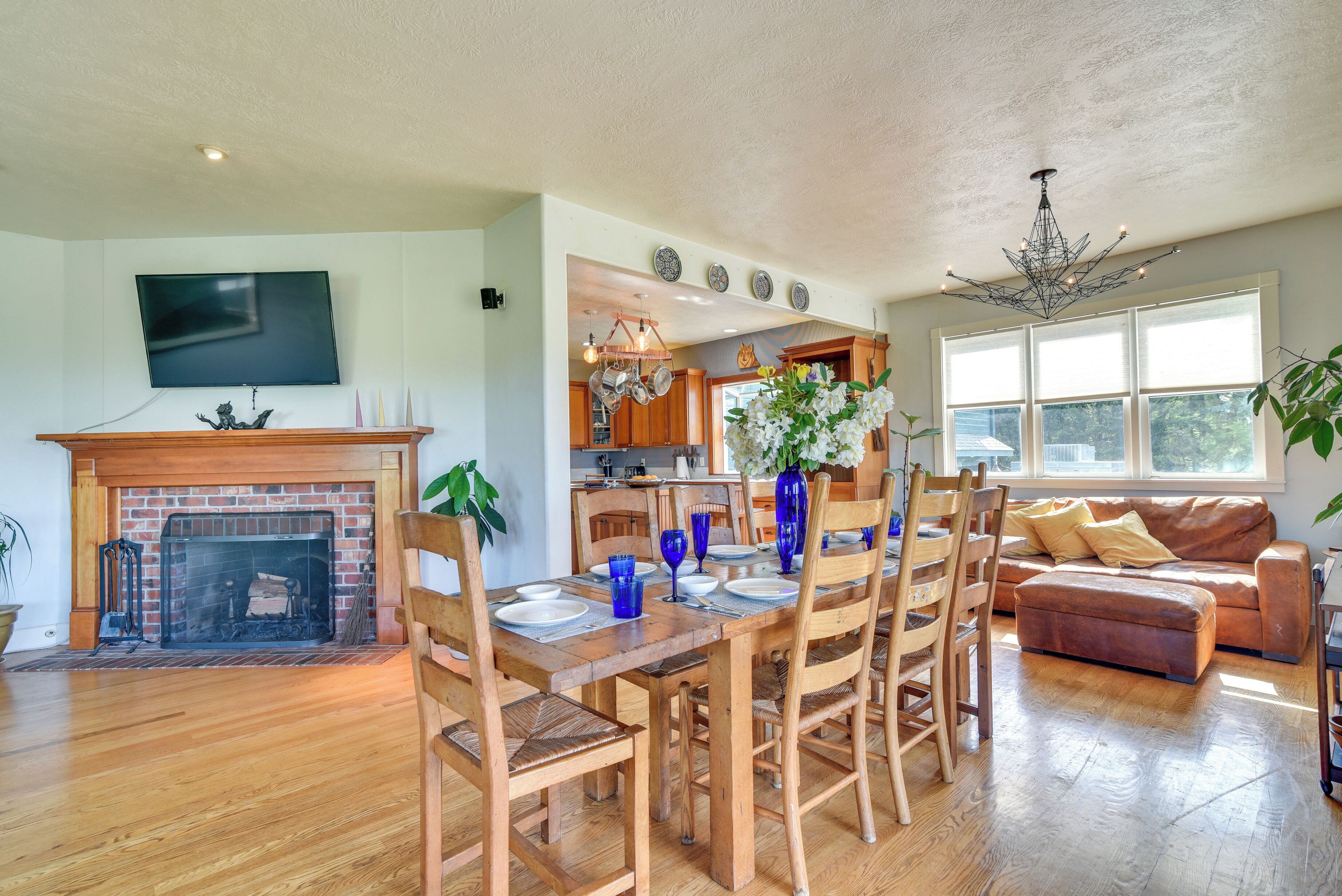 A spacious living room with a fireplace, wooden dining table, and a comfortable sofa.