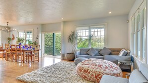 A spacious living area with a wooden dining table, grey sofa, and a large shaggy rug. - Rainier Home on 20 Acres w/ Blueberry Farm! (Rainier)