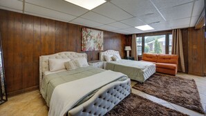 A bedroom with two beds, wooden paneling, a large window, and a painting on the wall. - Mechanicsville Vacation Rental ~ 8 Mi to Richmond (Mechanicsville)
